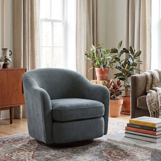 Modern living room with a blue swivel chair, marble coffee table, mid-century sideboard, and patterned area rug.