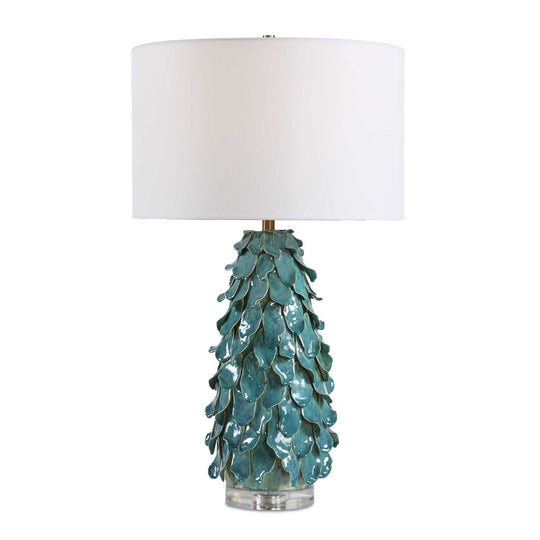 Table lamp with a textured turquoise base and white shade on a white background