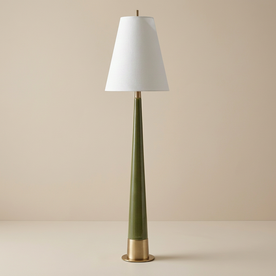mid-century modern style table lamp with a tall, slender tapered ceramic body in a glossy moss green finish. The lamp features a brushed gold metallic base and matching neck hardware, topped with a crisp white tapered fabric drum shade