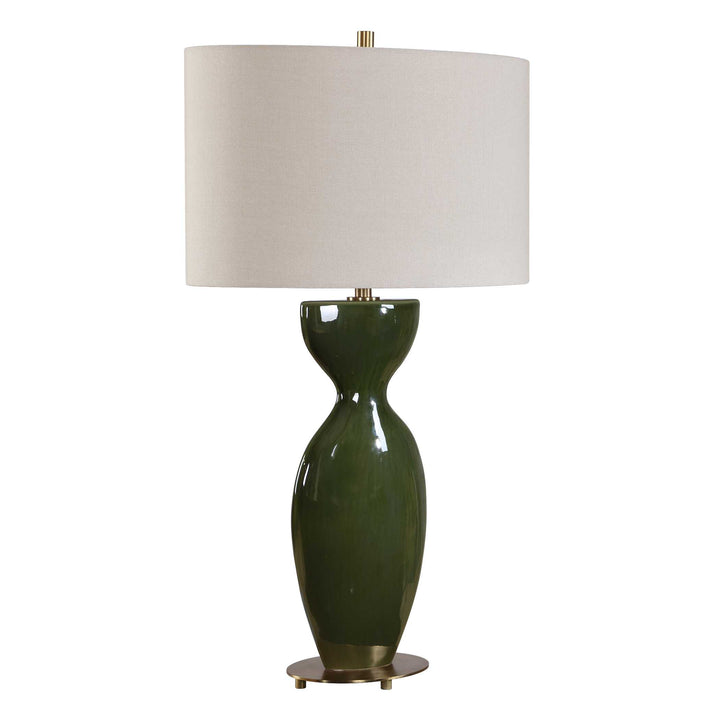 olive-green ceramic lamp base topped by a oval linen shade, brass accents at neck and base