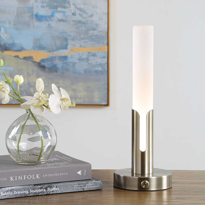 A modern table lamp with a frosted white cylindrical shade and a brushed brass-finish base