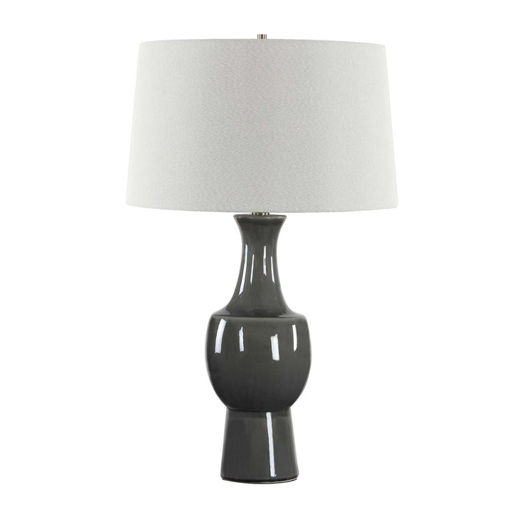 a table lamp with a glossy dark gray ceramic base and a textured off-white fabric drum shade