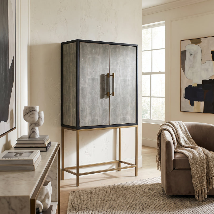 Modern living room featuring a chic grey shagreen bar cabinet with gold legs, marble console table, and a cozy armchair.
