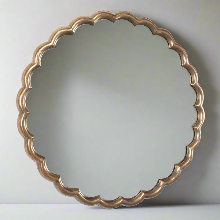 Round mirror with a decorative gold frame on a white background