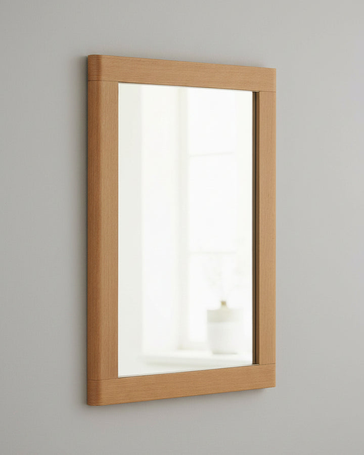 A rectangular wall mirror with a natural oak wood frame, shown at a slight angle