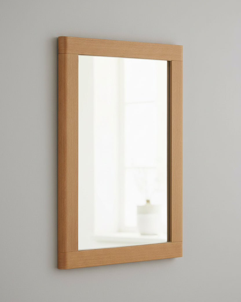 A rectangular wall mirror with a natural oak wood frame, shown at a slight angle