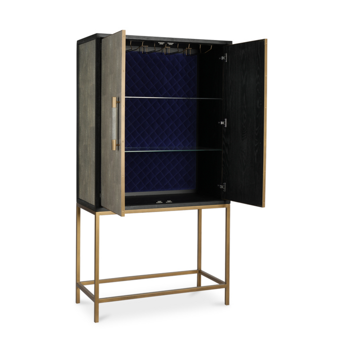 tall bar cabinet with open double doors, blue quilted velvet back panel, two glass shelves, matte black oak wooden exterior with shagreen panels, brass metal legs