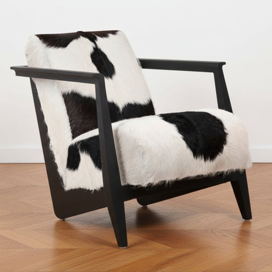 A modern rustic arm chair with a teak wood frame and black and white goat hide upholstery.