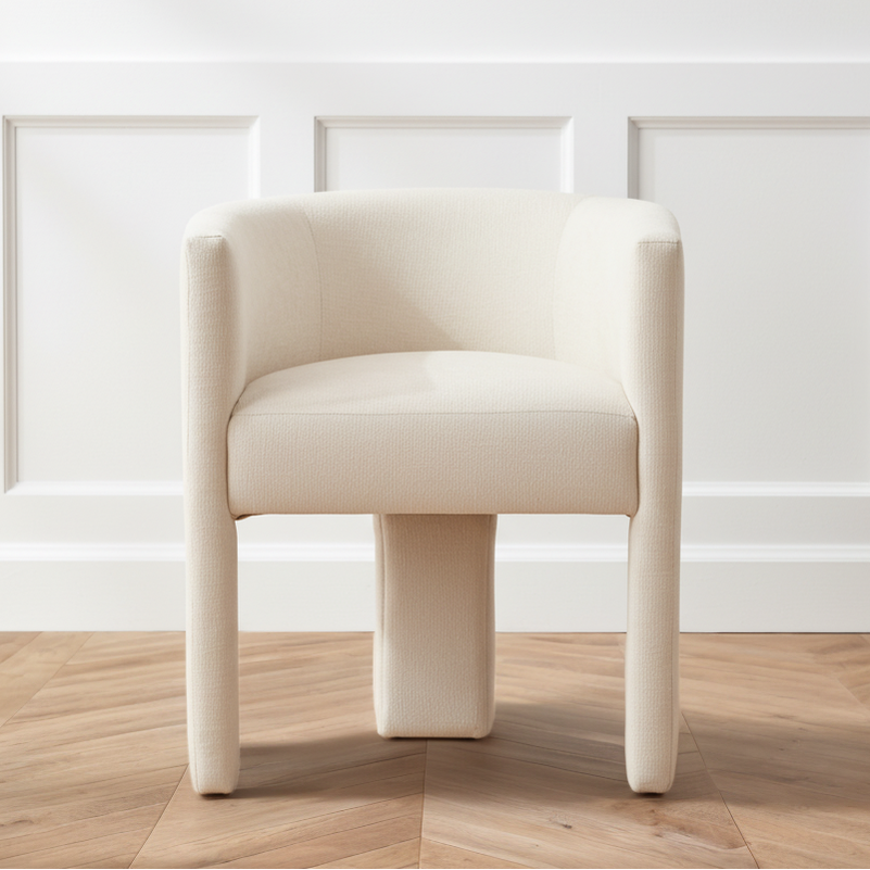 Beige chair on a wooden floor with a white paneled wall background