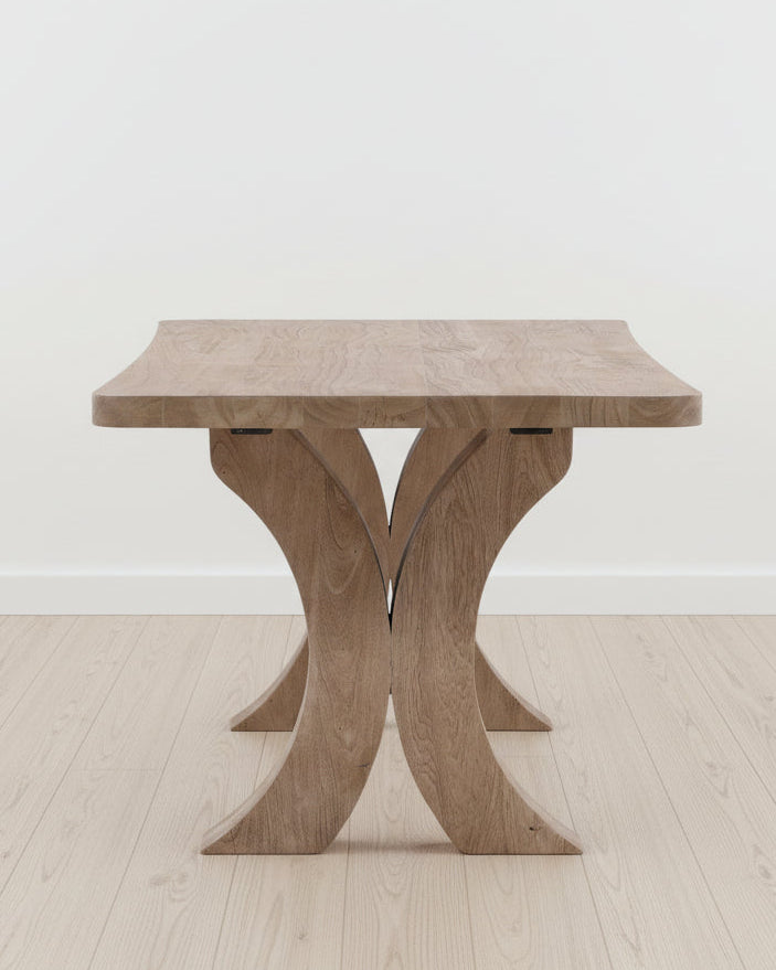 Wooden dining table with unique X-shaped legs in a neutral indoor background