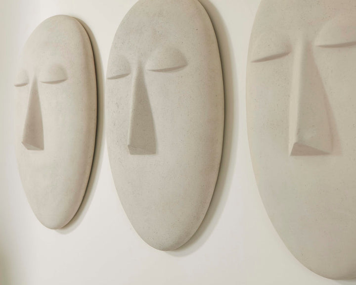 Three abstract ceramic face sculptures on a white wall
