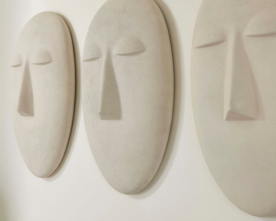 Three abstract ceramic face sculptures on a white wall