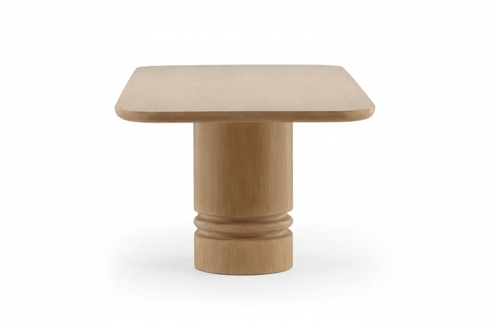 Wooden dining table with a light oak finish, rectangular top with rounded corners, supported by two thick cylindrical legs