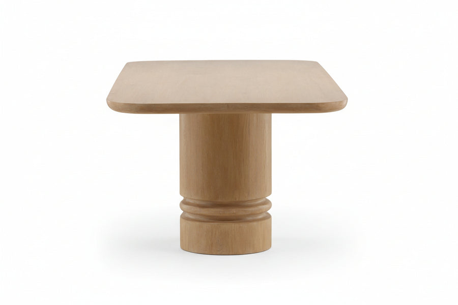 Wooden dining table with a light oak finish, rectangular top with rounded corners, supported by two thick cylindrical legs