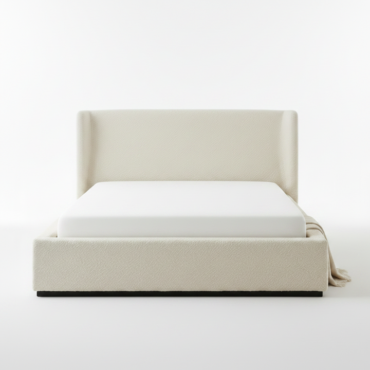 Beige upholstered bed with white mattress on a plain background
