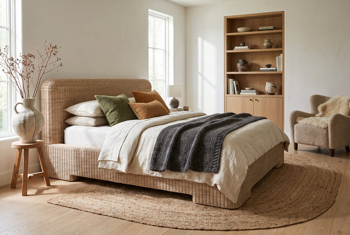 Modern organic bedroom with a woven rattan bed, neutral linen bedding, cozy textures, and built-in wood shelving.