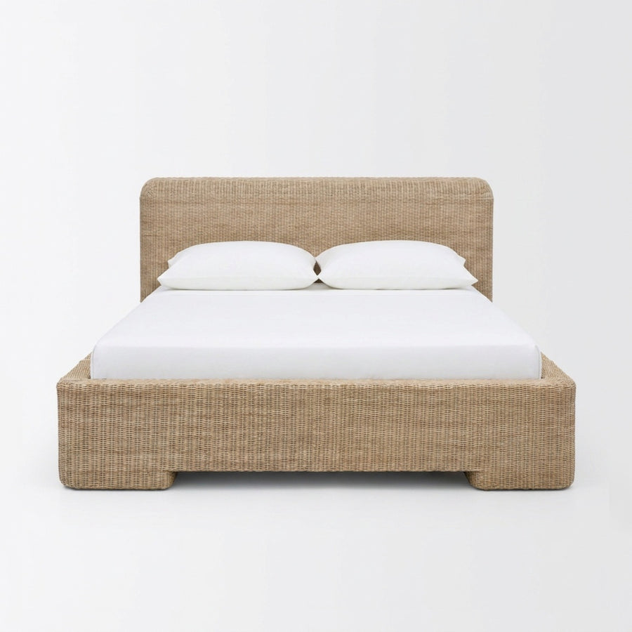 A low-profile platform bed with a woven natural fiber headboard and matching footboard, styled with a white mattress and two white pillows against a plain white background.