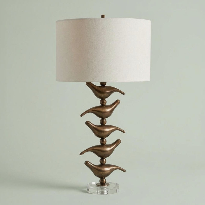 Decorative table lamp with bronze bird-like design on a light green background