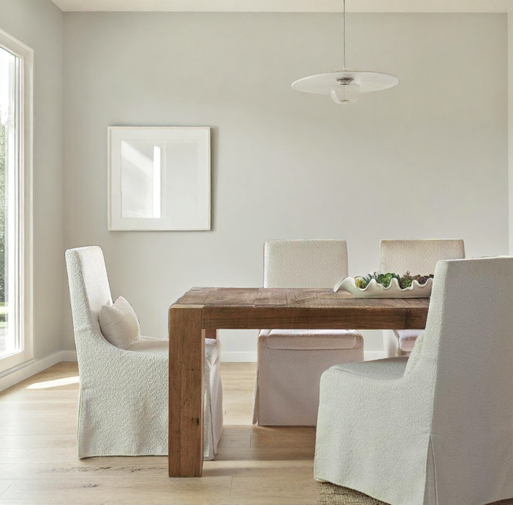 Dining room with wooden table, white chairs, and a chandelier.
