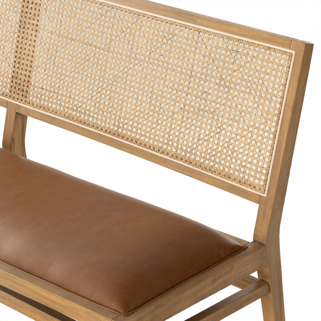 A stylish wooden bench featuring a cane backrest and a padded brown seat.