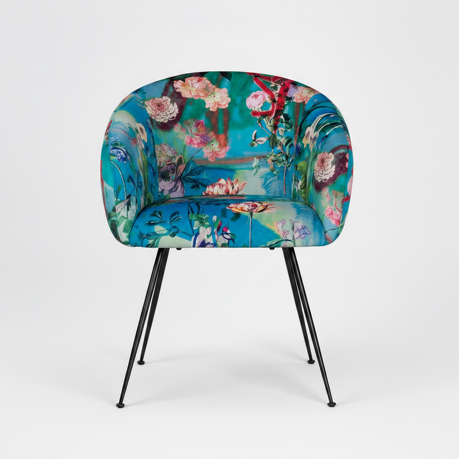 A modern accent chair with a vibrant floral print upholstery in shades of teal, blue, pink, and green, supported by slim black metal legs, shown against a light gray studio background.