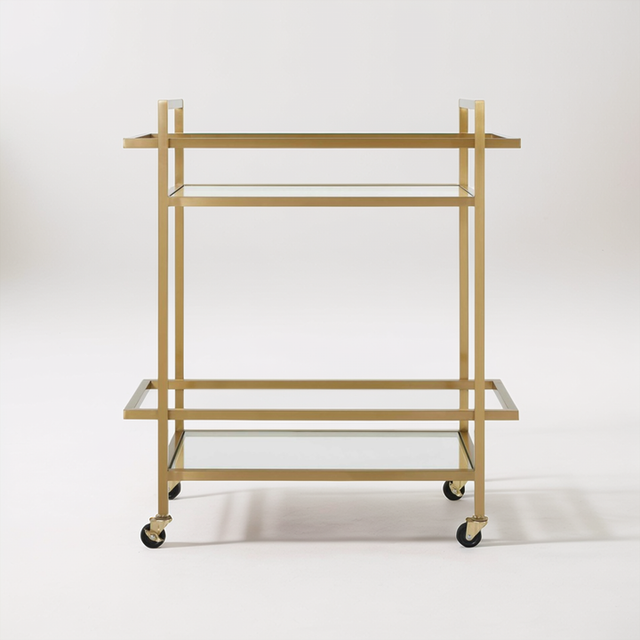 Gold bar cart with glass shelves in a room