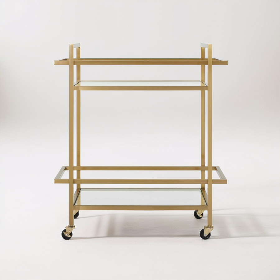 Gold bar cart with glass shelves in a room