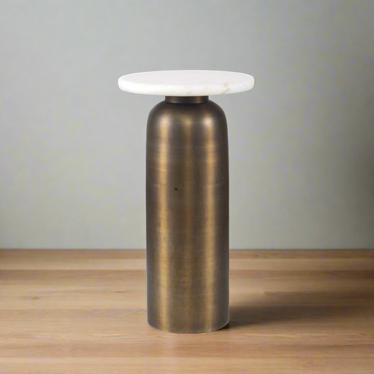 Bronze cylindrical side table with white marble top on a wooden floor