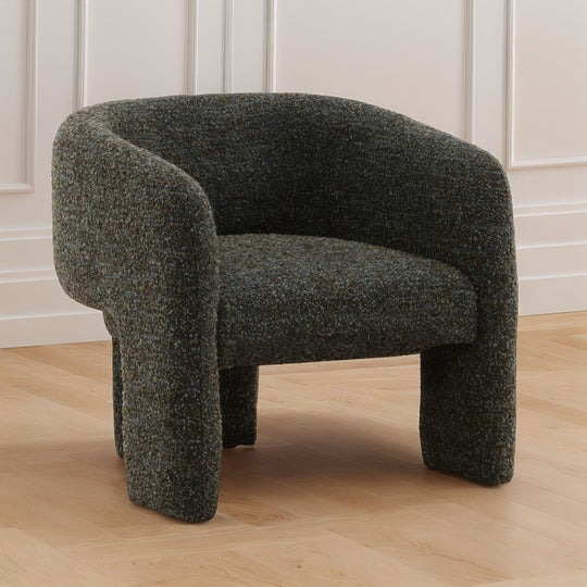 blue-green textured armchair on a wooden floor with white paneled walls.