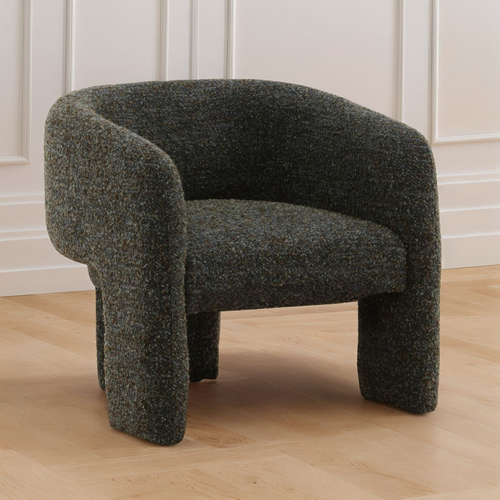 blue-green textured armchair on a wooden floor with white paneled walls.