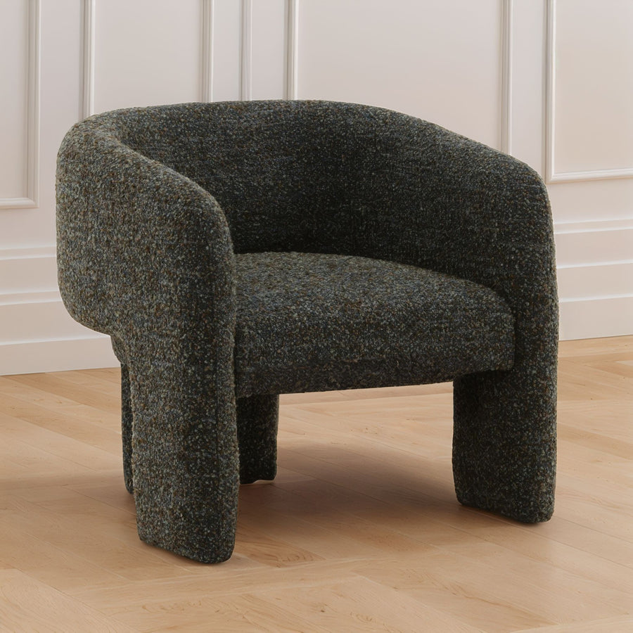 blue-green textured armchair on a wooden floor with white paneled walls.