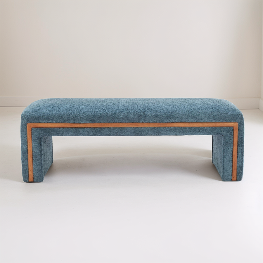 Blue upholstered bench with brown trim on a white background
