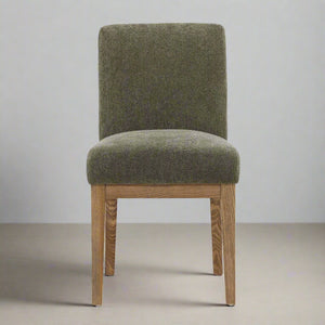 Green upholstered chair with wooden legs on a neutral background