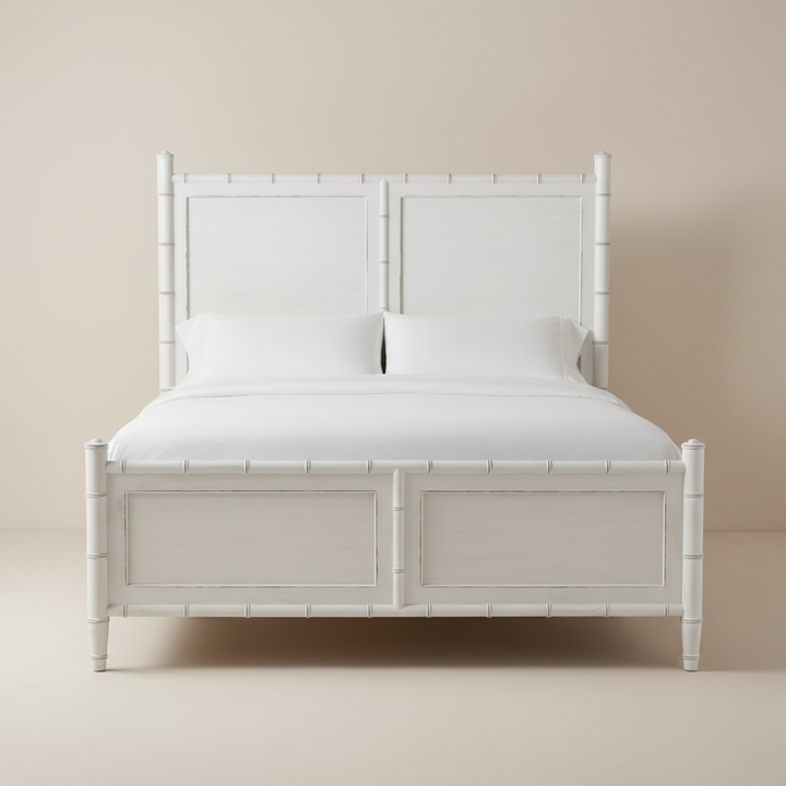White wooden bed frame with white bedding on a beige background