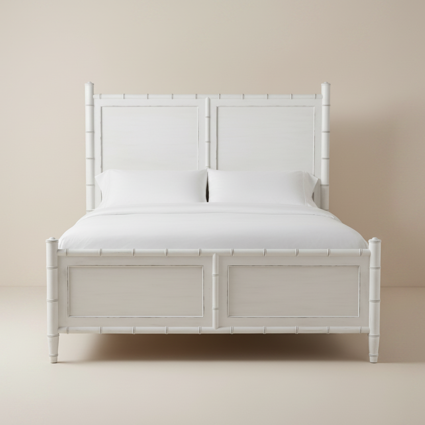 White wooden bed frame with white bedding on a beige background