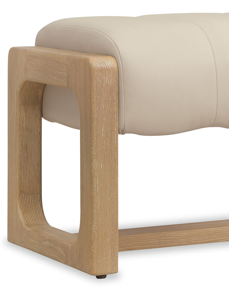 A modern bench features a cushioned light beige seat and a sturdy wooden frame with a unique rounded design.