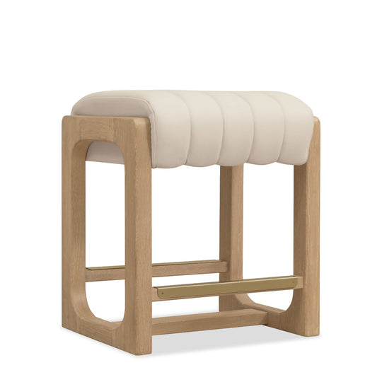 Modern wooden stool with a creamy upholstered seat featuring tufted design and a gold footrest.