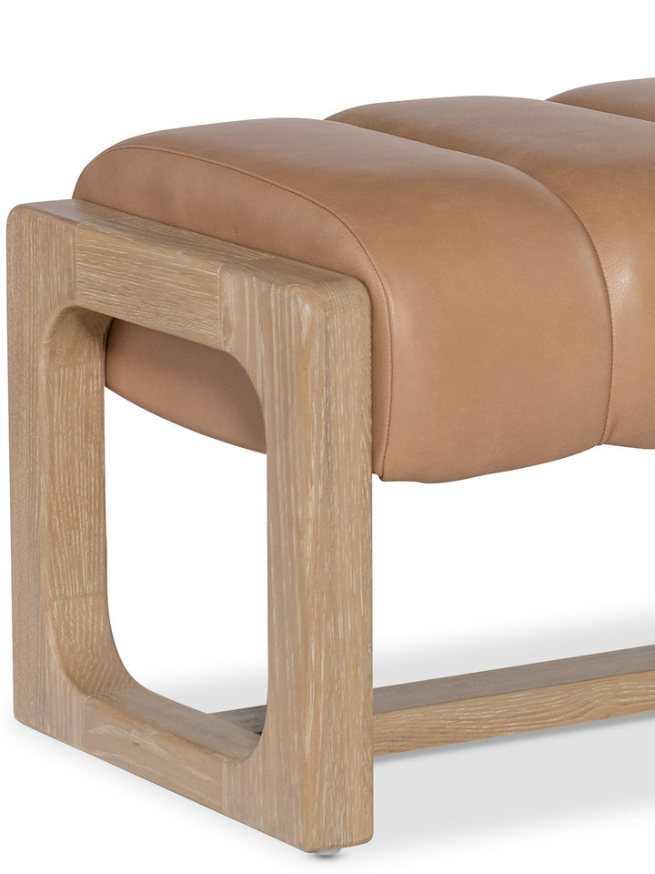 A modern bench with tan leather upholstery and a light wood frame featuring a distinctive cut-out design on the sides.