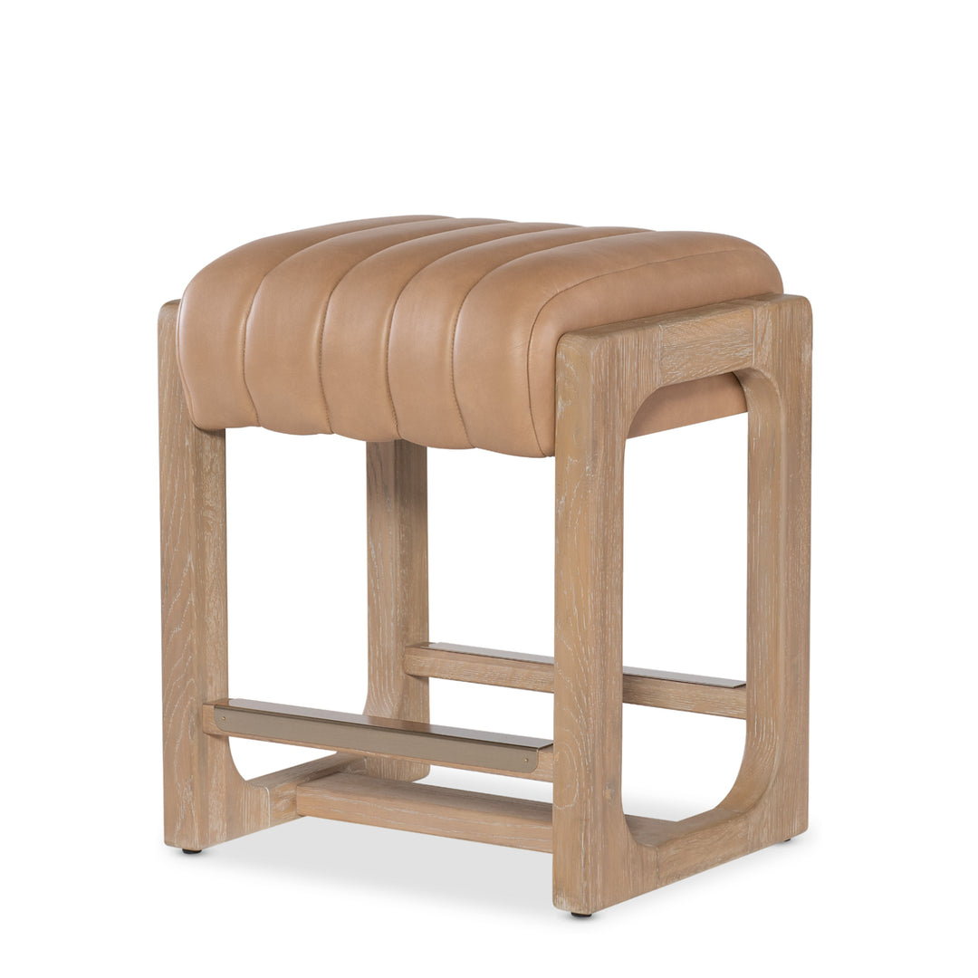 Angled view of a tan leather banyan counter stool wooden legs against a white background.