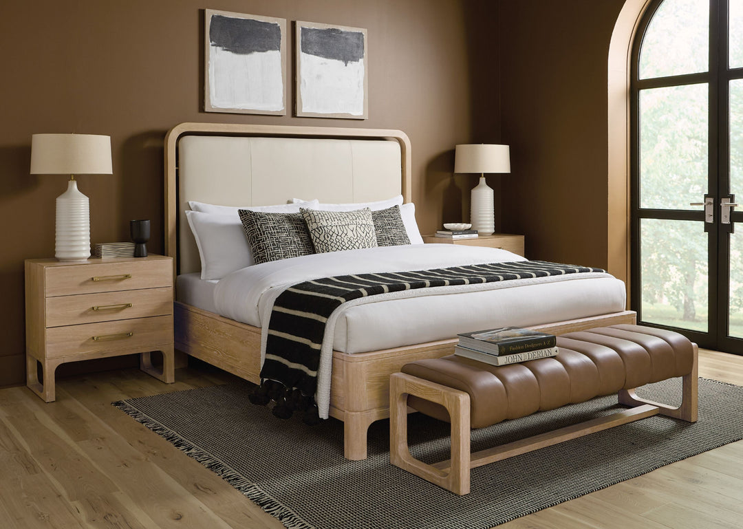 Modern bedroom with a wooden bed, stylish pillows, a leather bench, lamps, a wooden dress of 3 drawers.