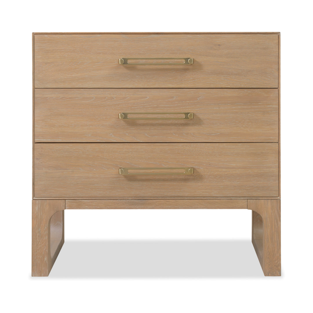 Front view of a banyan wood dresser with a light oak finish, three drawers, brass handles, and open-cut wooden legs for support.