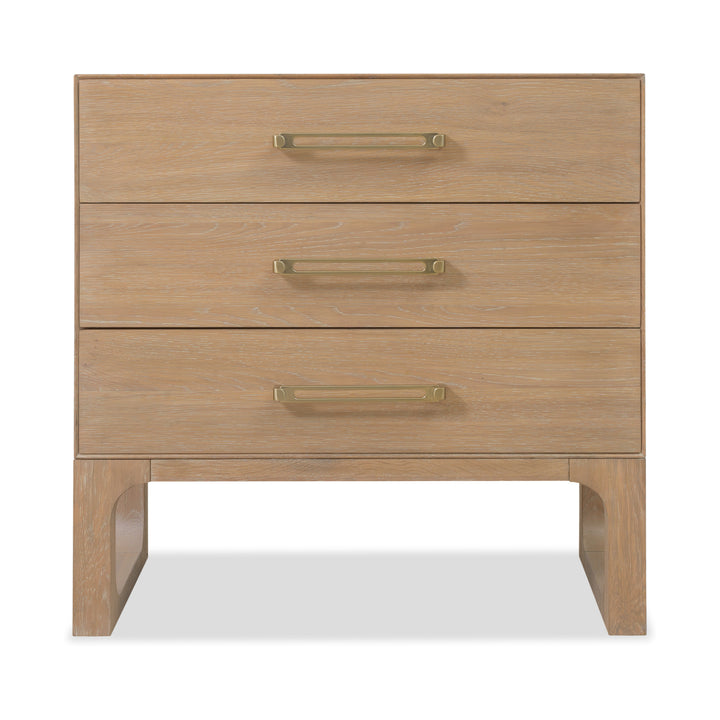 Front view of a banyan wood dresser with a light oak finish, three drawers, brass handles, and open-cut wooden legs for support.