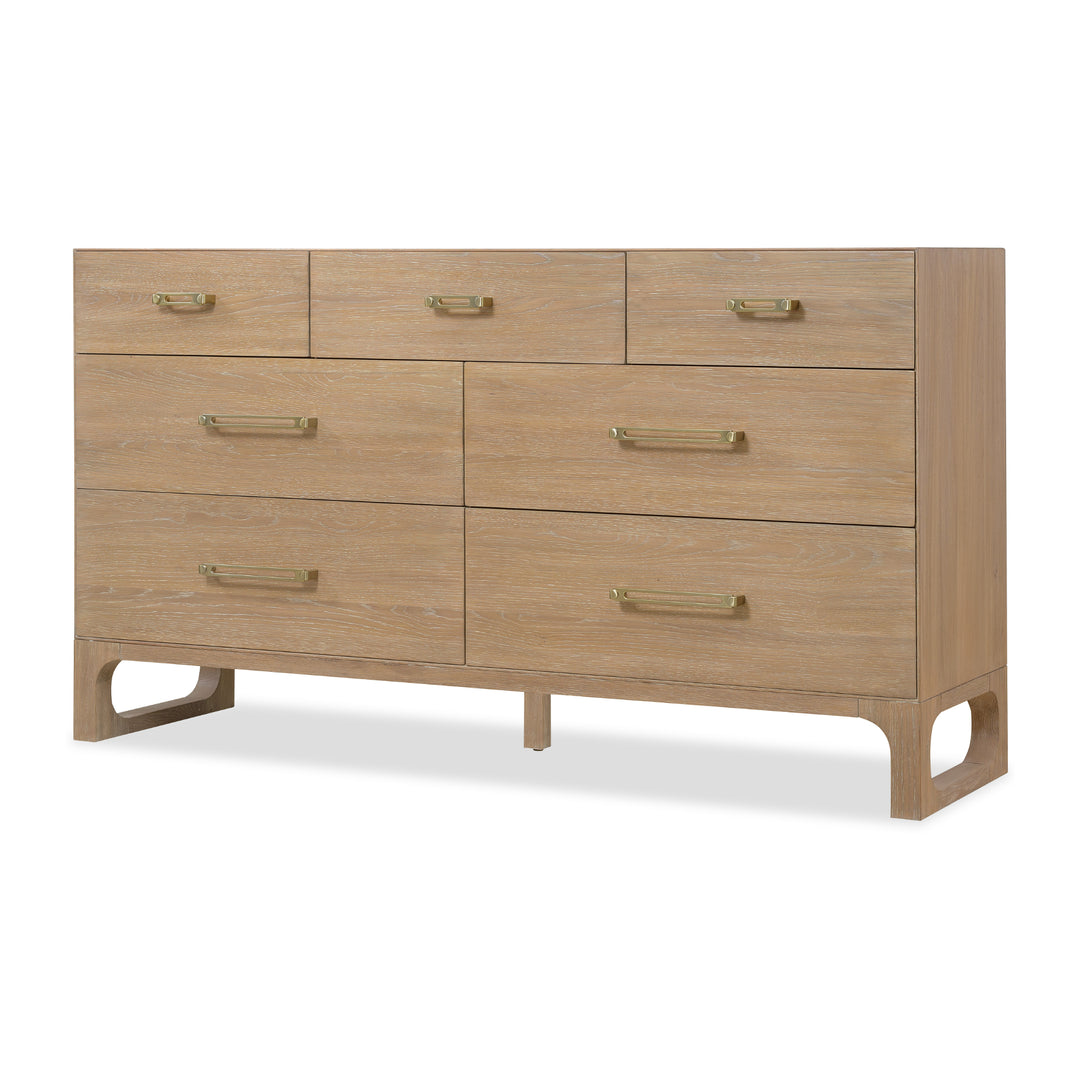 Angled view of a wooden dresser with a light oak finish, 7 drawers, and brass handles against white background.