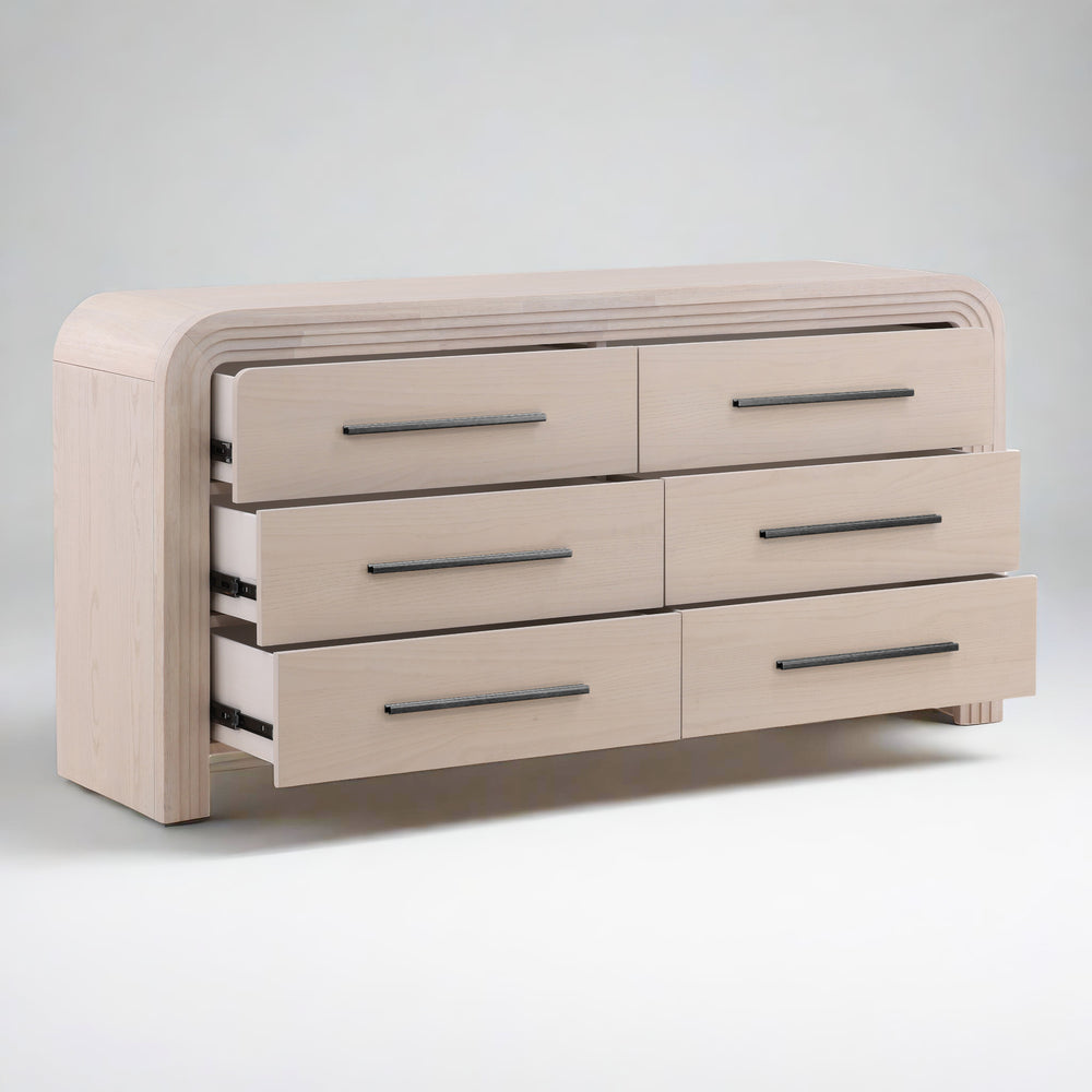 Light-colored wooden dresser with six drawers, showcasing sleek handles and a rounded top edge.