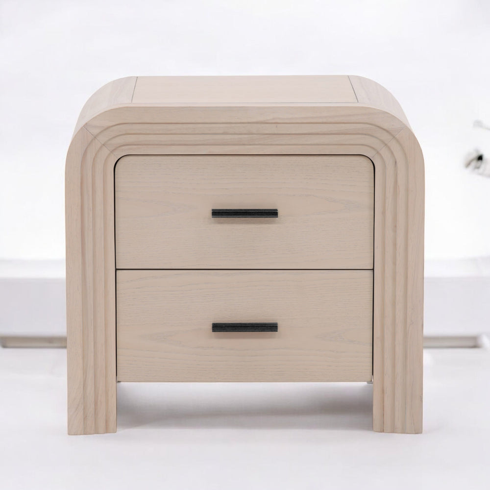 A modern light wood nightstand with a curved design featuring two drawers and sleek black handles.