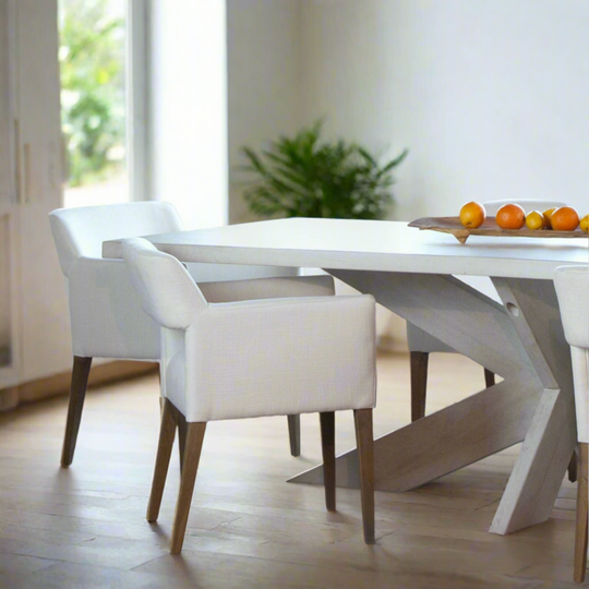 Modern dining area with a white table and chairs in a bright room.