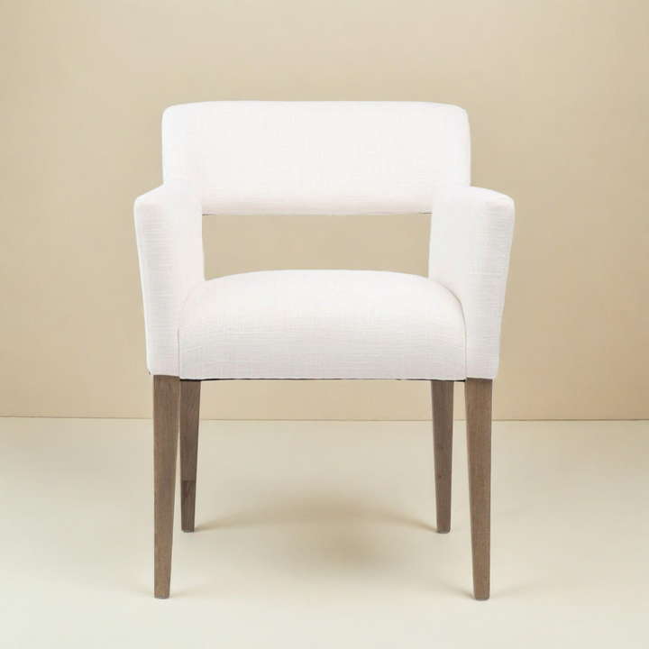 White upholstered armchair with wooden legs on a beige background
