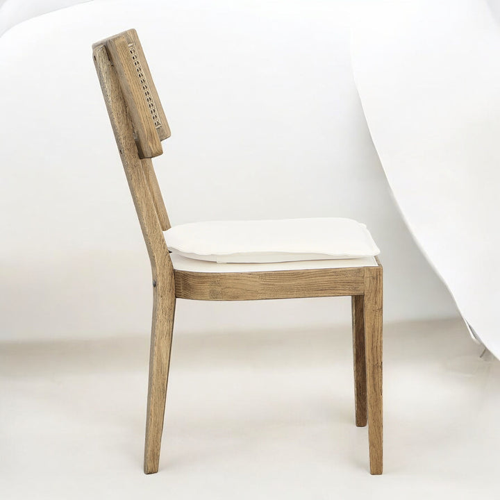 Side view of a wooden dining chair with a light cushion.