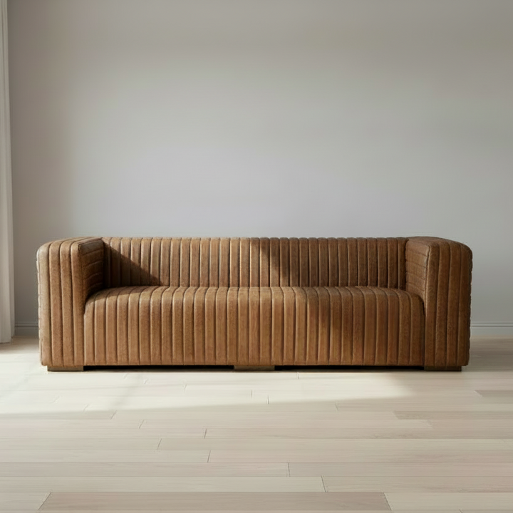 A vintage brown leather sofa with a solid wood frame, featuring channel-stitched top-grain leather
