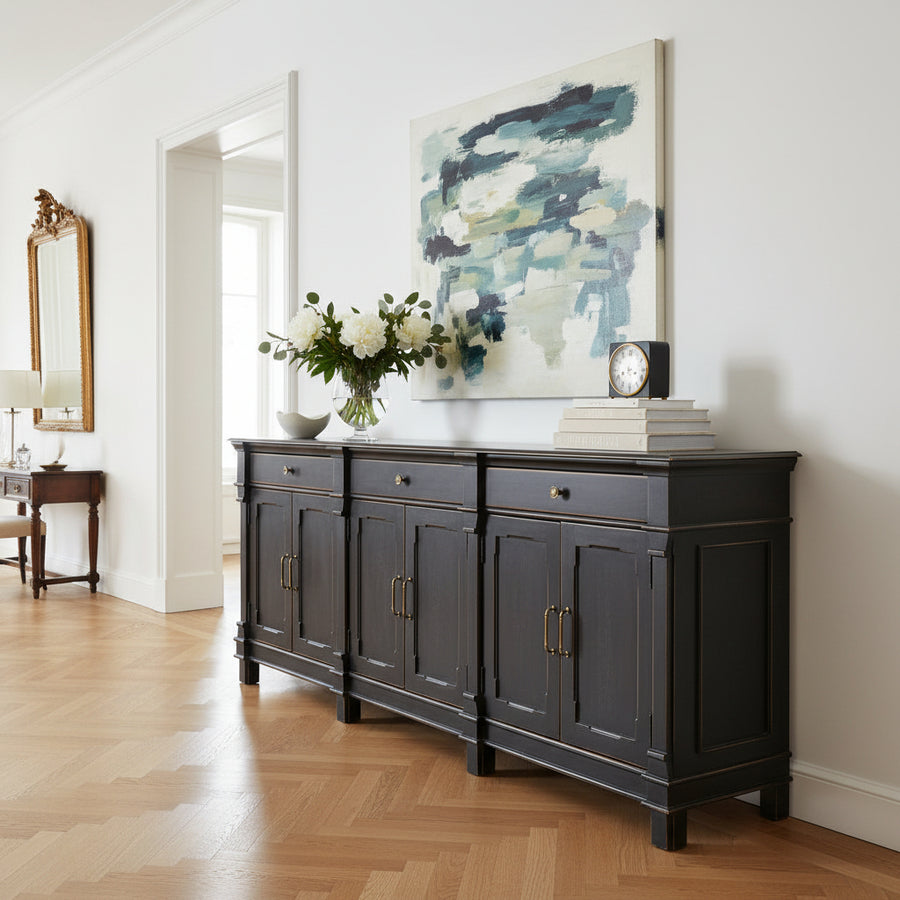 A wooden sideboard cabinet with distressed black finish and brass hardware